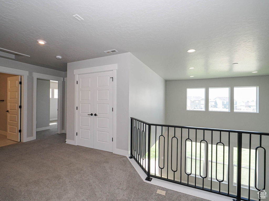 Hallway with carpet floors, a textured ceiling, and recessed lighting