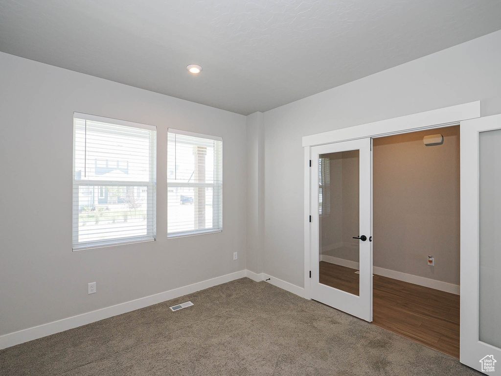 Carpeted empty room with french doors and recessed lighting