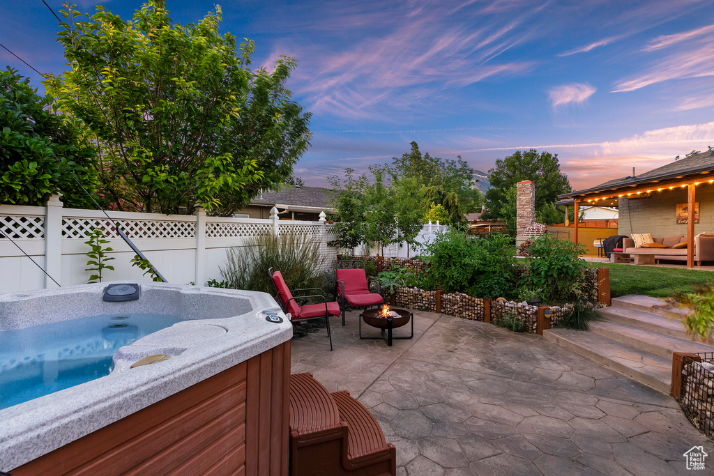 Fenced backyard featuring an outdoor living space with a fire pit, a patio area, and a hot tub