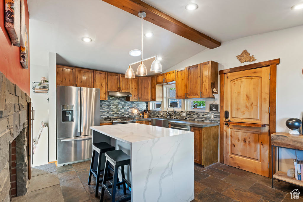 Kitchen with appliances with stainless steel finishes, backsplash, brown cabinets, stone tile floors, and recessed lighting