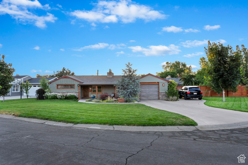 Ranch-style house with driveway, a garage, and a chimney