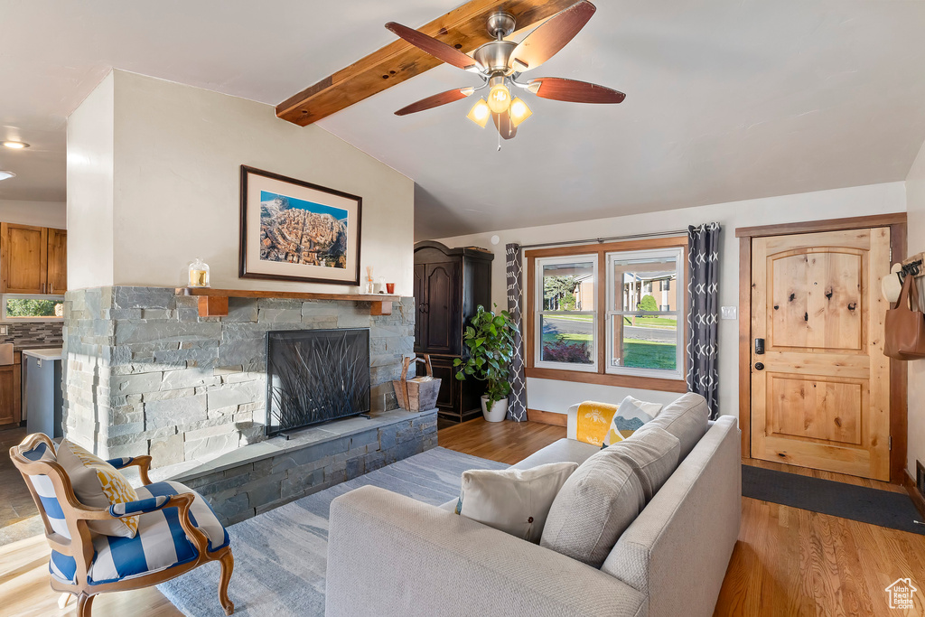 Living room featuring wood finished floors, ceiling fan, a stone fireplace, and recessed lighting