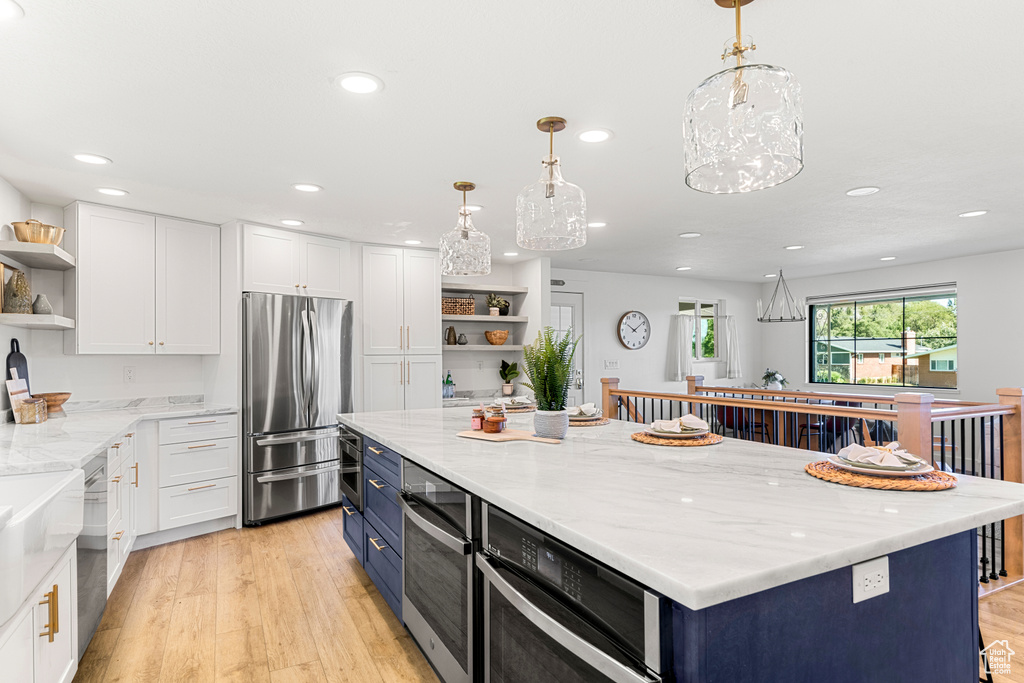 Kitchen with open shelves, freestanding refrigerator, blue cabinetry, white cabinets, and recessed lighting