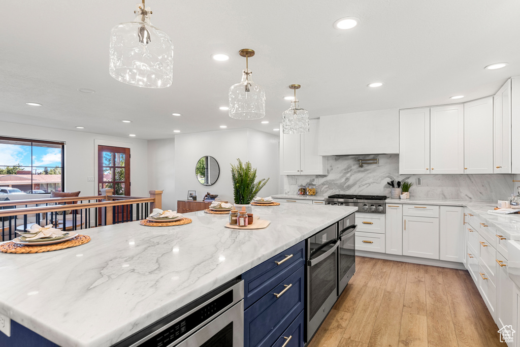 Kitchen with blue cabinets, recessed lighting, white cabinetry, stainless steel appliances, and light wood-style floors