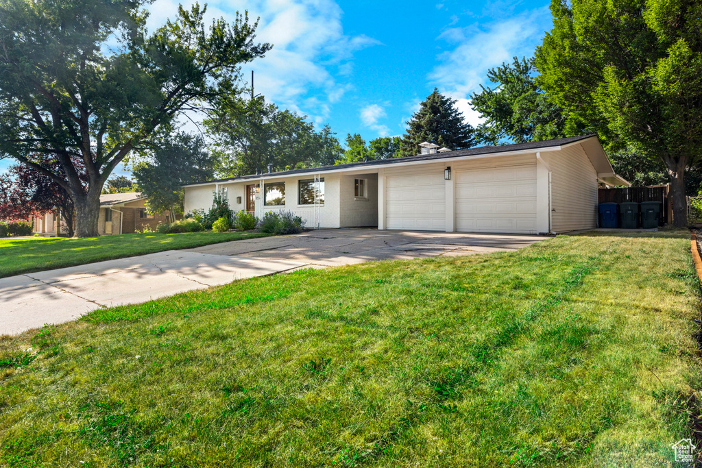 Single story home with concrete driveway, a garage, and a front lawn