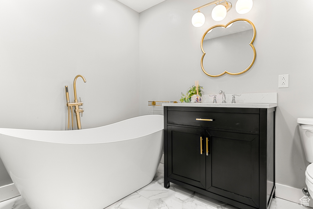 Full bathroom with marble finish floors, a freestanding tub, and vanity