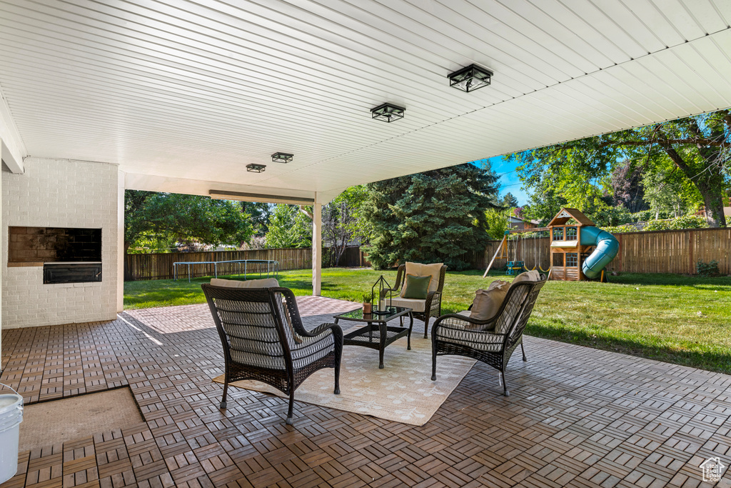 Fenced backyard featuring a trampoline, a playground, a patio, and an outdoor hangout area