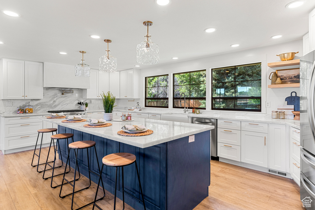 Kitchen featuring appliances with stainless steel finishes, recessed lighting, light wood-style floors, a center island, and white cabinets