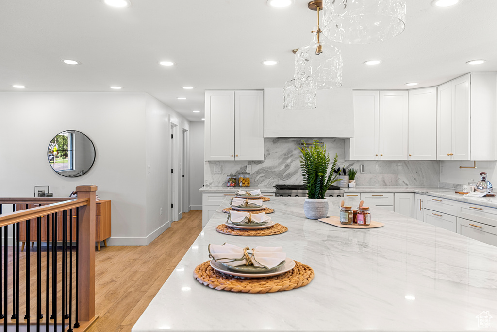 Kitchen with recessed lighting, decorative backsplash, custom range hood, white cabinets, and light stone counters