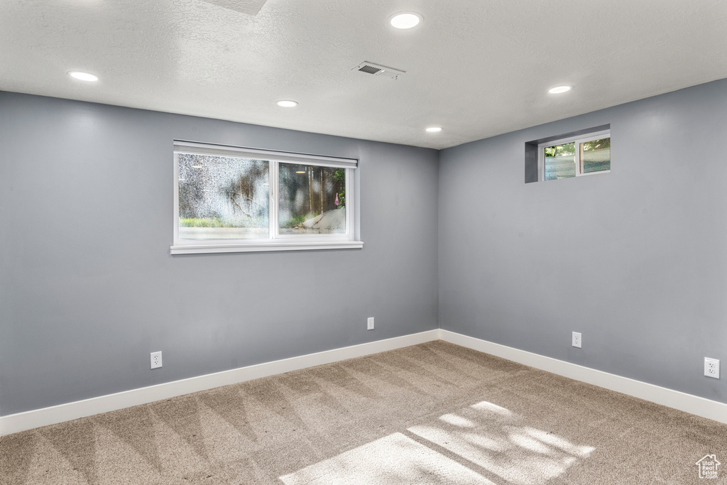 Empty room featuring carpet, recessed lighting, and a textured ceiling