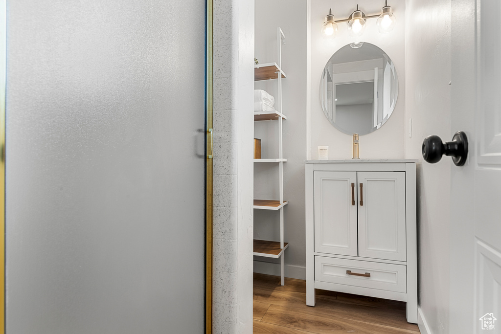 Bathroom with wood finished floors, an enclosed shower, and vanity