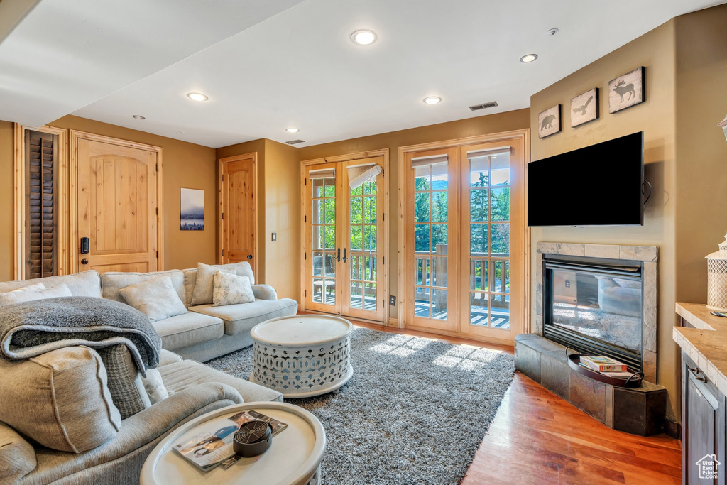 Living area featuring wood finished floors, a glass covered fireplace, and recessed lighting