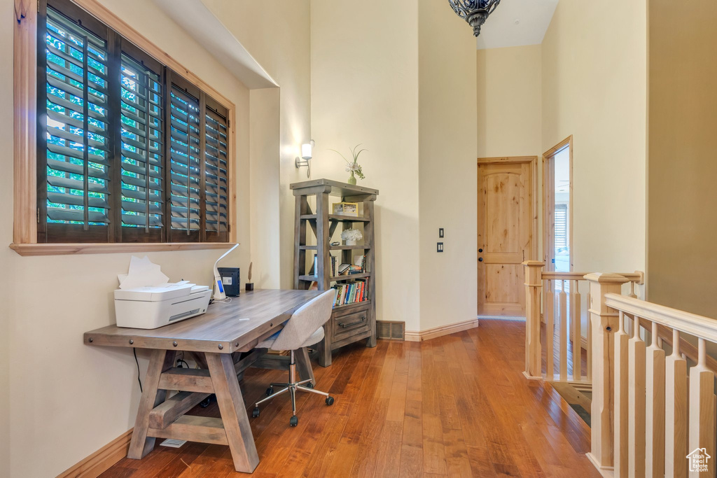 Home office with hardwood / wood-style floors and a towering ceiling