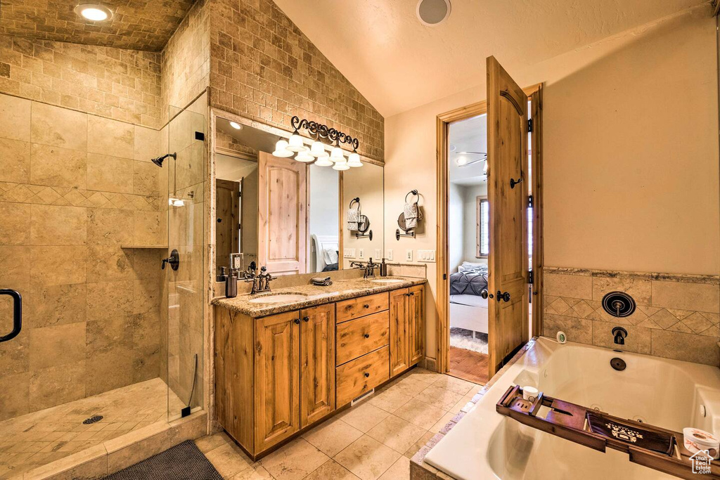 Bathroom with a bath, double vanity, tile patterned flooring, vaulted ceiling, and a stall shower