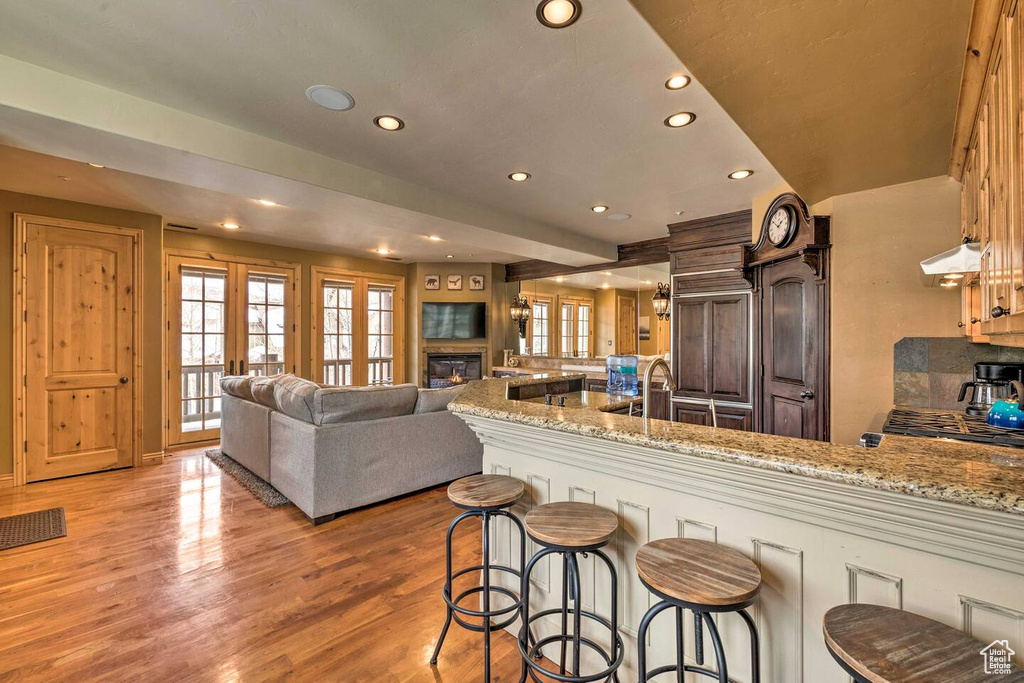 Kitchen featuring a peninsula, recessed lighting, extractor fan, a kitchen breakfast bar, and light wood-style floors