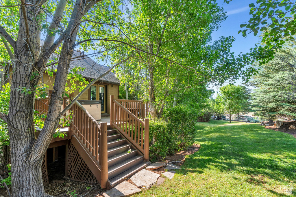 View of grassy yard with stairs and a deck