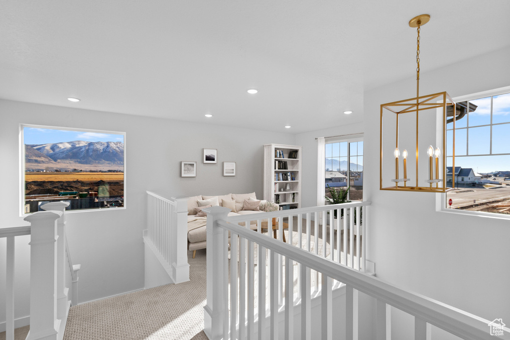Corridor with an upstairs landing, carpet floors, recessed lighting, and a chandelier