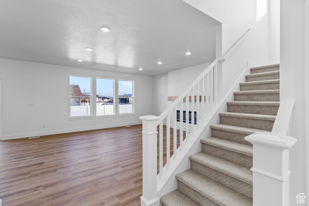 Staircase featuring recessed lighting and wood finished floors