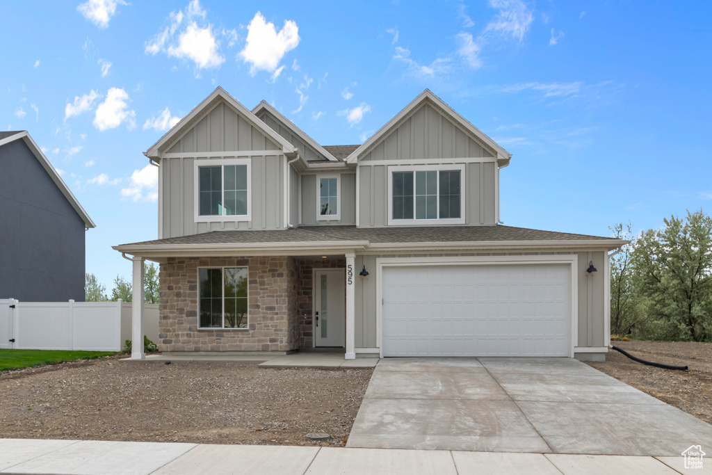 View of front of house featuring concrete driveway, a garage, board and batten siding, stone siding, and covered porch