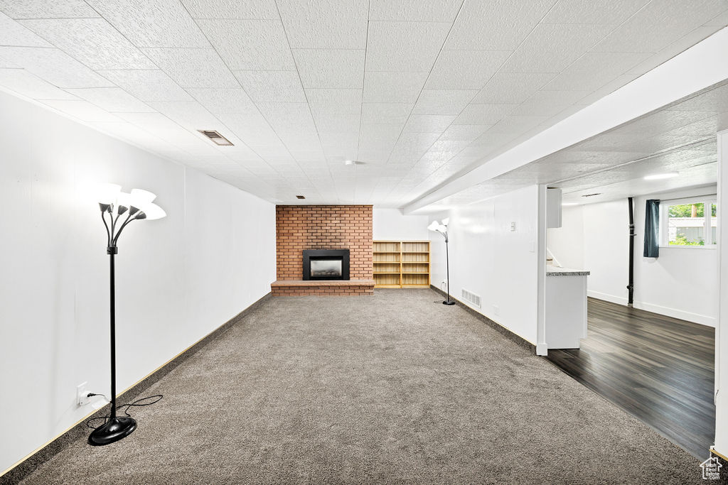 Below grade area with dark colored carpet and a brick fireplace
