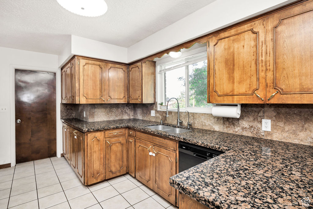 Kitchen with brown cabinets, light tile patterned floors, backsplash, and a textured ceiling