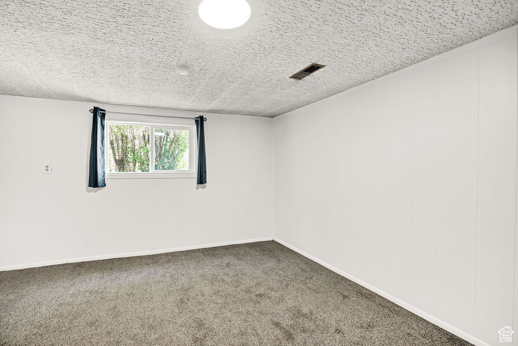 Empty room featuring a textured ceiling and carpet