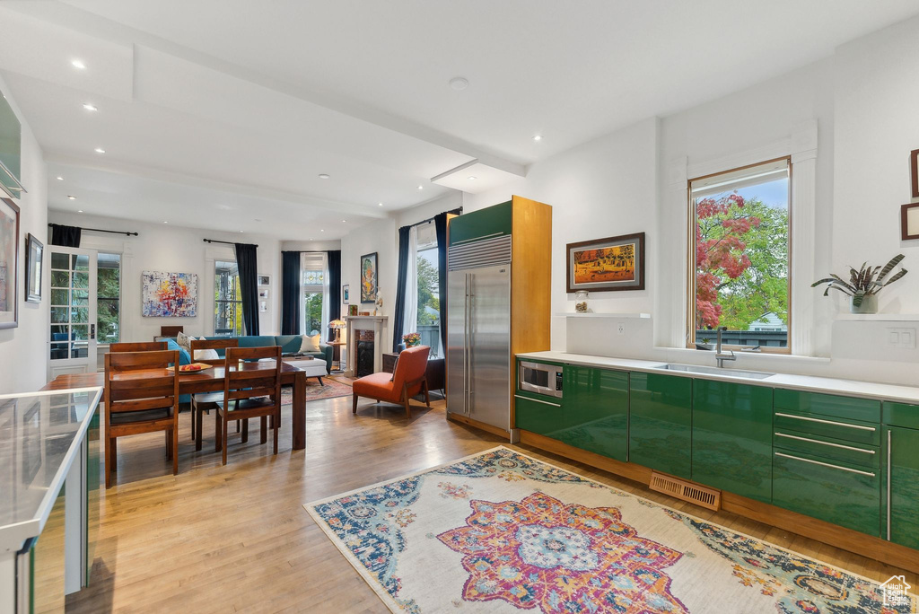 Kitchen with built in appliances, green cabinetry, light wood finished floors, plenty of natural light, and recessed lighting
