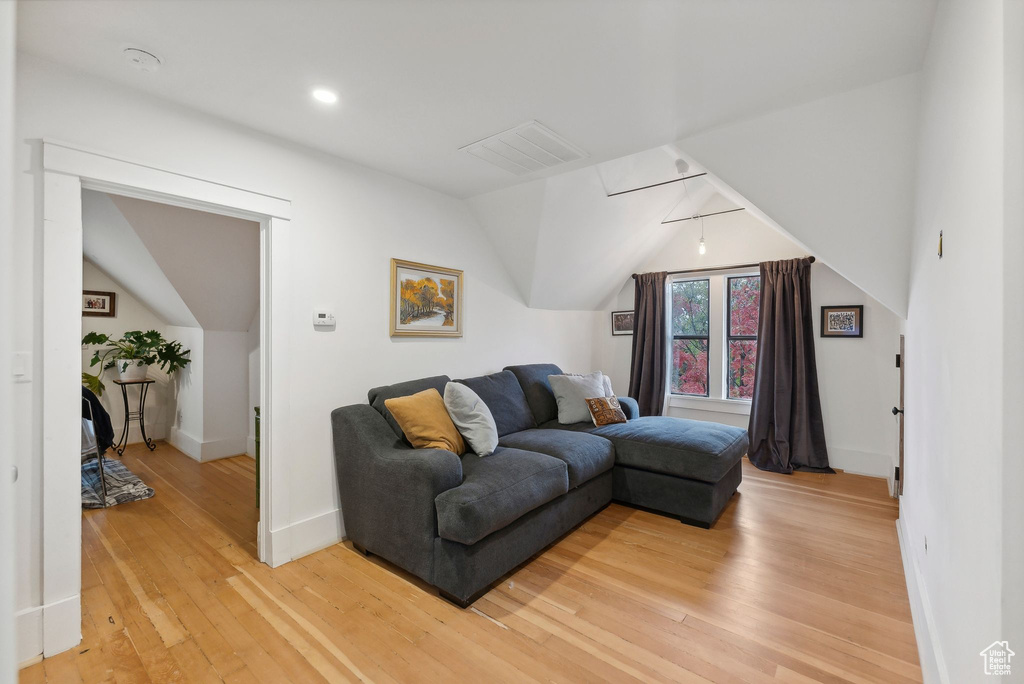 Living area with vaulted ceiling, light wood-style flooring, and recessed lighting