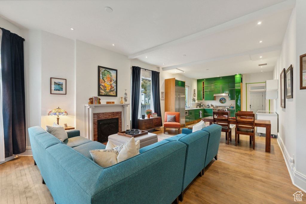 Living area featuring light wood-type flooring, a brick fireplace, recessed lighting, and radiator heating unit