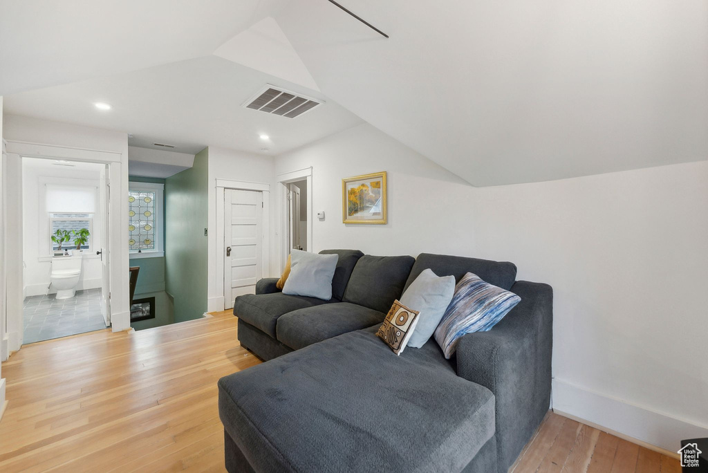 Living room with vaulted ceiling, wood finished floors, and recessed lighting