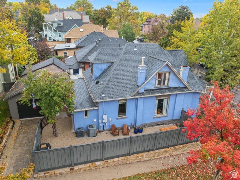 Rear view of house with roof with shingles, a fenced backyard, a chimney, and a residential view