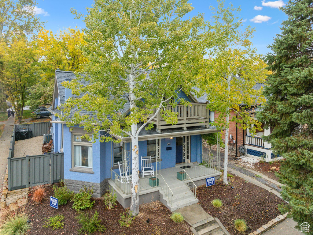 View of property hidden behind natural elements with covered porch and a gate