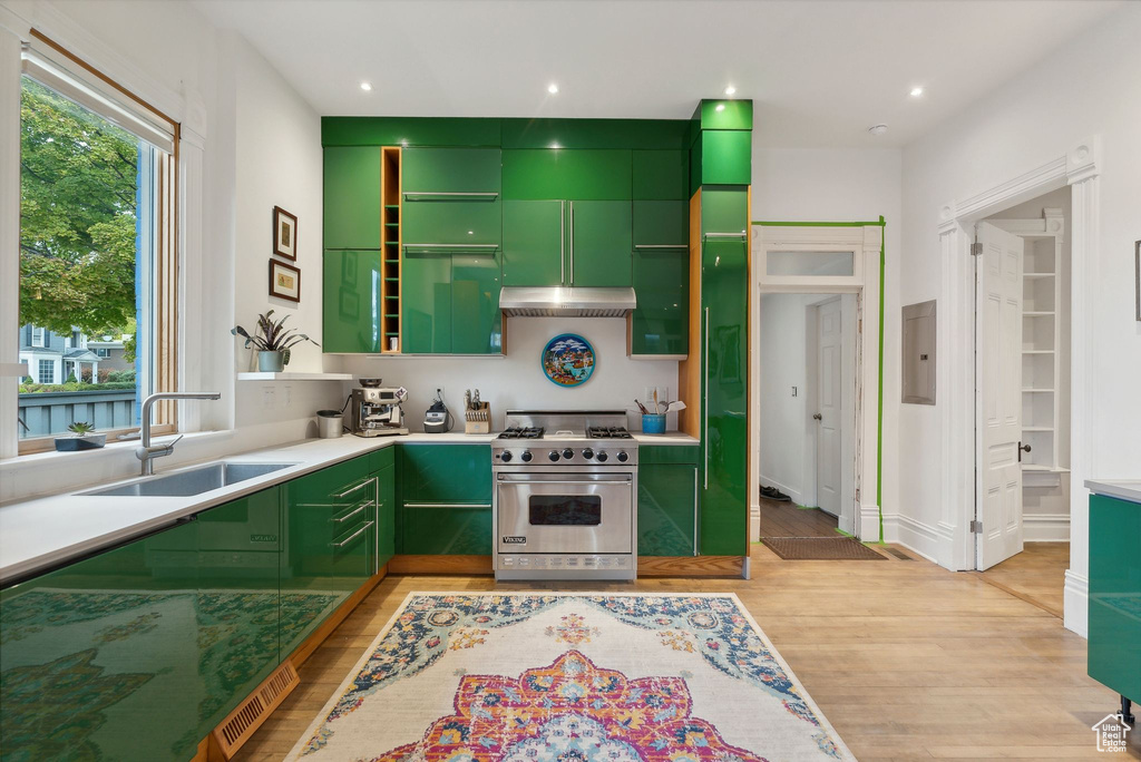Kitchen with luxury range, green cabinetry, light wood-type flooring, electric panel, and recessed lighting