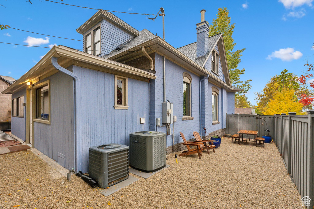 Rear view of property with a chimney, a fenced backyard, brick siding, and roof with shingles