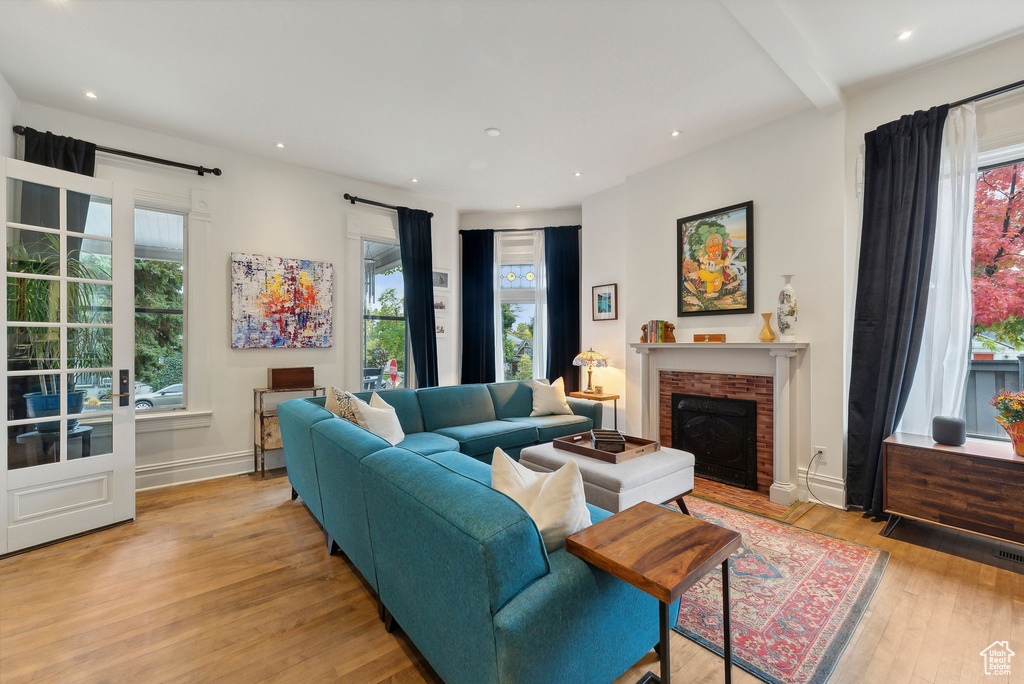 Living area with plenty of natural light, light wood-type flooring, a fireplace, and recessed lighting