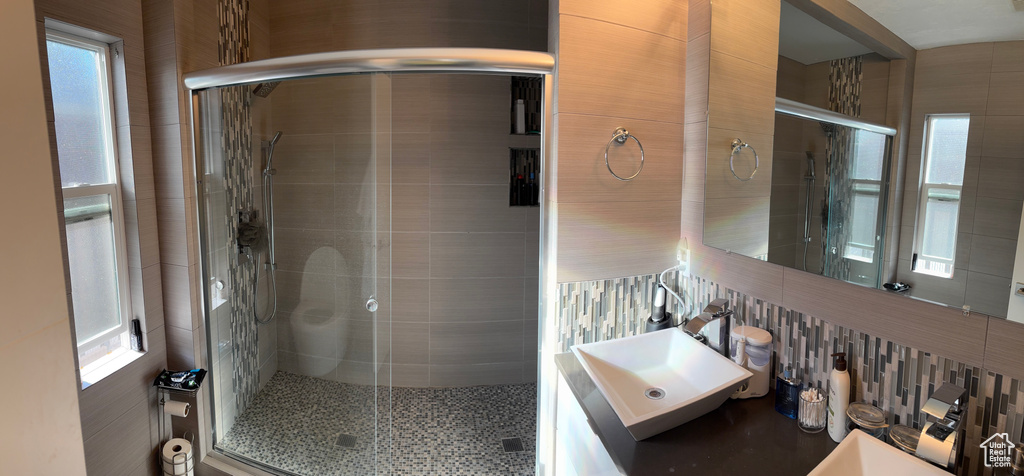 Bathroom with a stall shower, tile walls, and vanity