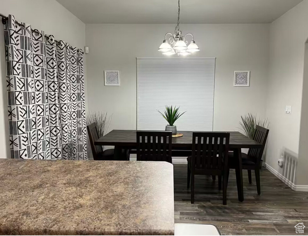 Dining space with a chandelier and dark wood-style floors