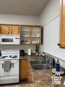Kitchen featuring white appliances, brown cabinets, and open shelves