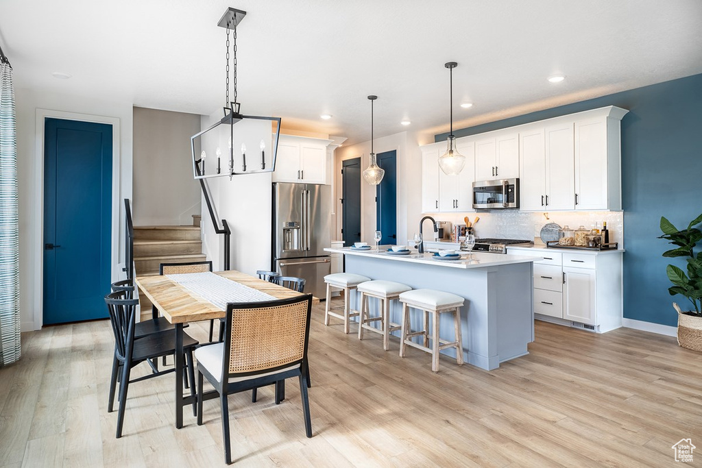 Dining space with light wood-style floors, stairs, and recessed lighting
