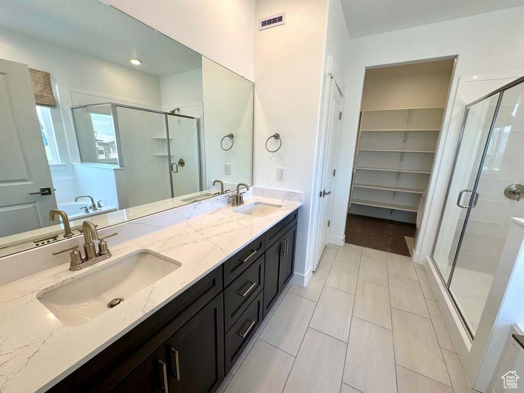 Full bathroom with a shower stall, double vanity, a bath, and a spacious closet