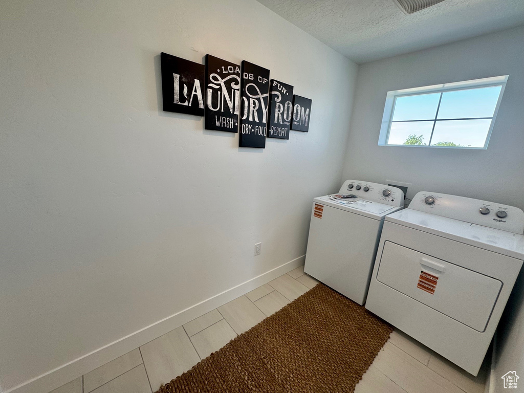 Laundry room with washing machine and dryer and a textured ceiling