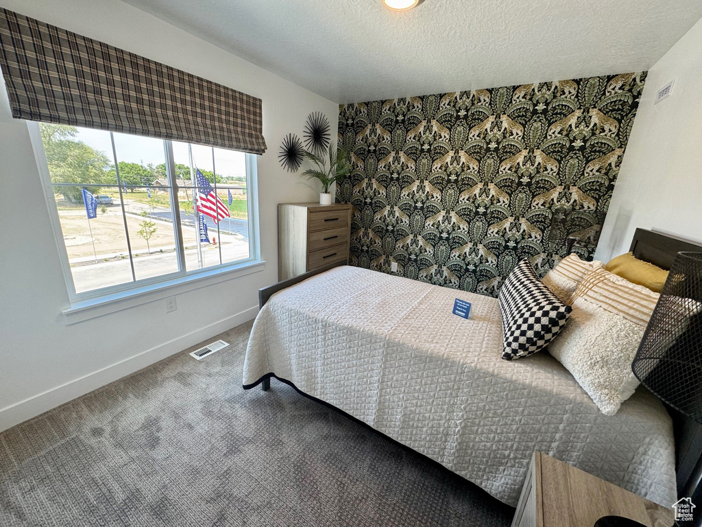Carpeted bedroom with a textured ceiling and an accent wall