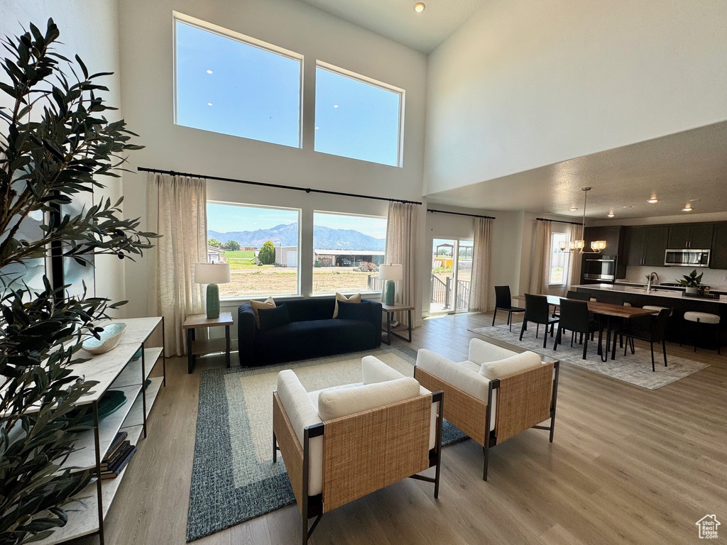 Living area with a towering ceiling, light wood-style flooring, healthy amount of natural light, a chandelier, and recessed lighting
