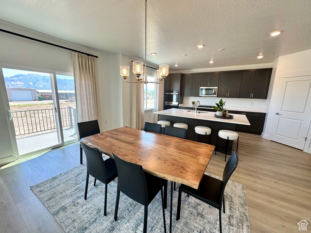 Dining space with a chandelier, a textured ceiling, light wood-type flooring, plenty of natural light, and recessed lighting