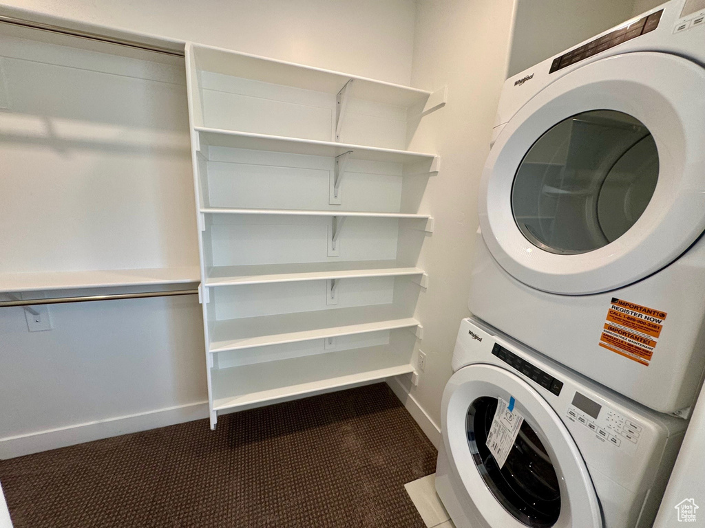 Washroom featuring stacked washing machine and dryer and baseboards