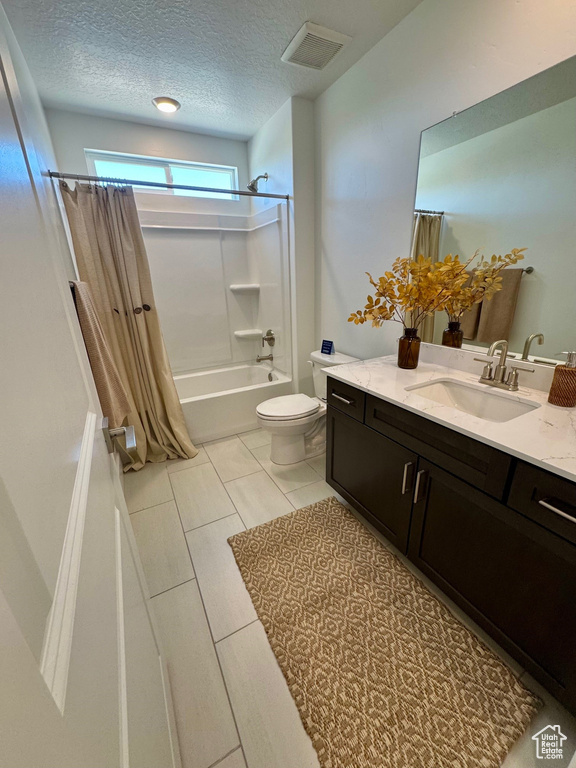 Full bath with shower / bath combination with curtain, vanity, and a textured ceiling