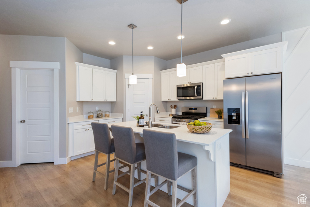 Kitchen with appliances with stainless steel finishes, light wood finished floors, light countertops, and recessed lighting