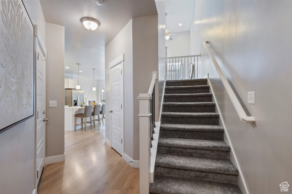 Staircase featuring ceiling fan, wood finished floors, and recessed lighting