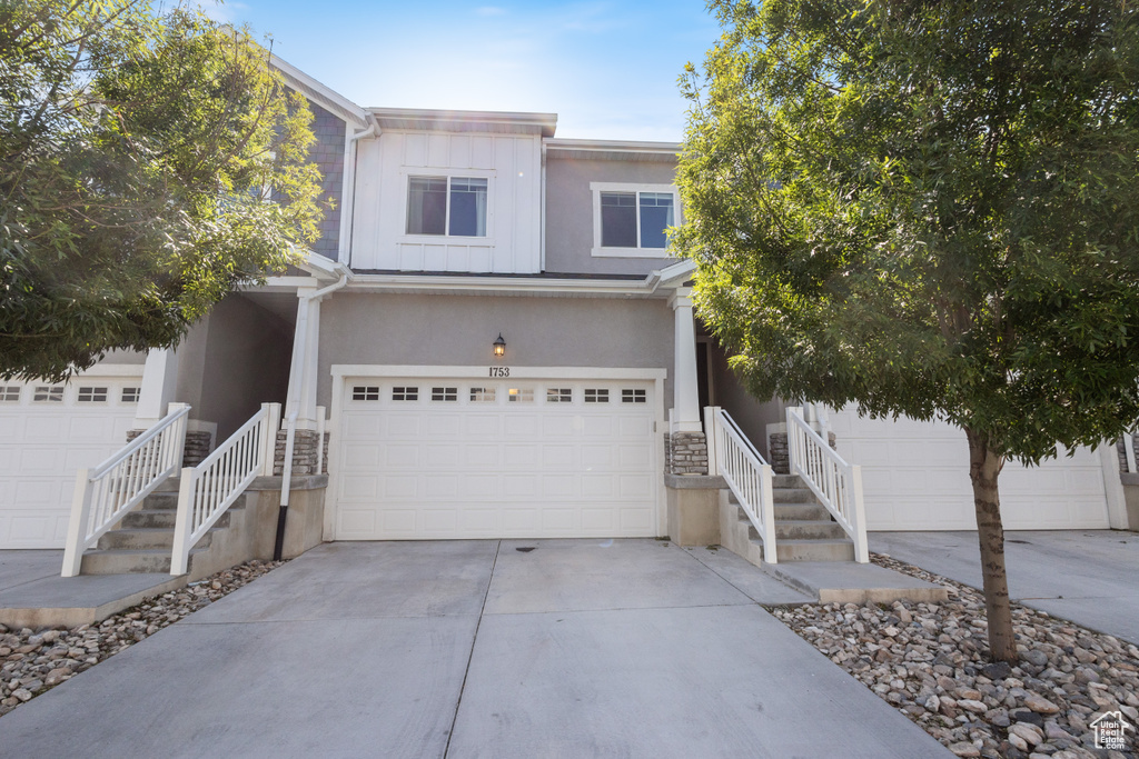 View of front of house with stone siding, driveway, stucco siding, and an attached garage