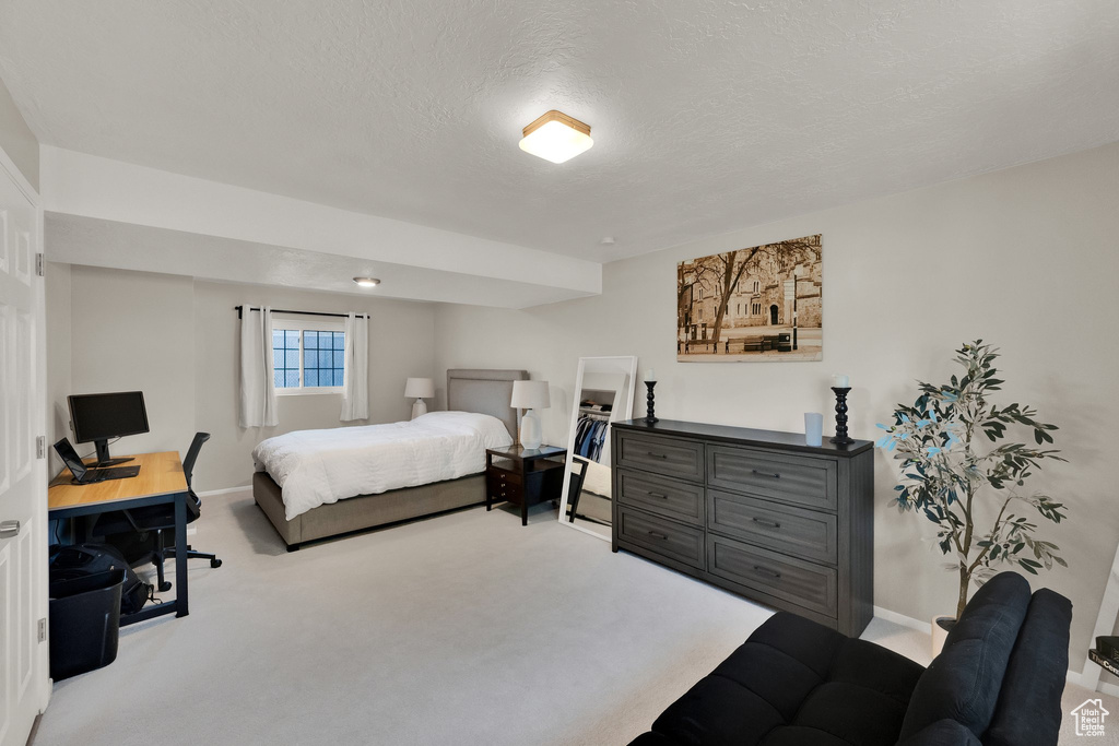 Carpeted bedroom with a textured ceiling and a desk
